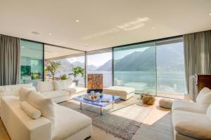 a living room with white furniture and a view of the water at Maison Sur l'Eau - Lugano Villa with View Terrace in Paradiso