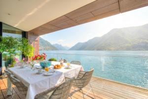 a table on a balcony with a view of the water at Maison Sur l'Eau - Lugano Villa with View Terrace in Paradiso