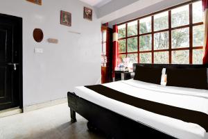 a bedroom with a black and white bed and a window at Hotel O Ghoom Formerly Aps Homestay in Darjeeling