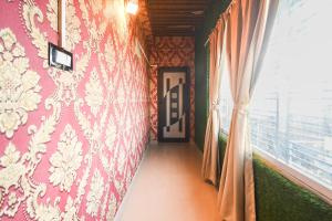 a hallway with a pink wall with a window at Hotel O Champasari Siliguri Formerly Four Fox Suits in Siliguri