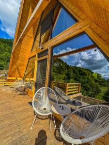 a deck with chairs and tables and a large window at Joy Chalet in Plaiu