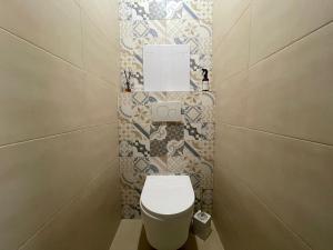 a bathroom with a toilet and a tile wall at Modern flat in a city in Humenné