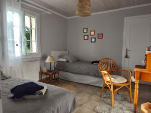 a bedroom with two beds and a chair and a window at Les Chambres D'Anel in Saint-Pourçain-sur-Besbre
