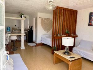 a living room with a bed and a table with a lamp at Departamento chichan nah in Progreso