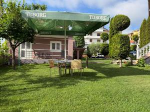 a table and chairs under a green umbrella in a yard at Topuzi Grand House in Pogradec