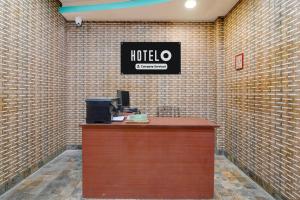 a hotel counter with a sign on a brick wall at Hotel O Eastern Crossway Siliguri Formerly Utsho in Siliguri