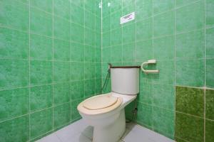 a bathroom with a toilet in a green tiled wall at Villa Tjokro 1 By ARBA in Sampal 2 +11 photos