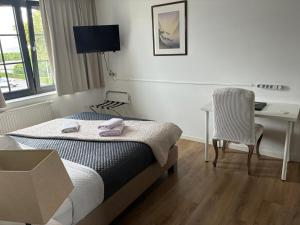 a bedroom with a bed and a desk and a chair at Hotel La Chaumiere in Asse