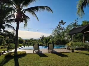 a pool with two chairs and a palm tree at Romantic Tropical Retreat with Sunset & Rice Field Views in Kuah +50 photos