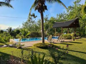 a resort with a swimming pool and a palm tree at Romantic Tropical Retreat with Sunset & Rice Field Views in Kuah