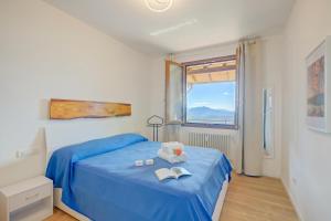 a bedroom with a blue bed and a window at Il Vecchio Faggio: Lake Maggiore view Terrace - Happy Rentals in Gignese