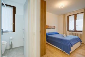 a bedroom with a blue bed and a bathroom at Il Vecchio Faggio: Lake Maggiore view Terrace - Happy Rentals in Gignese