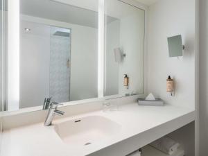 a bathroom with a sink and a mirror at Mercure Paris CDG Airport & Convention in Roissy-en-France