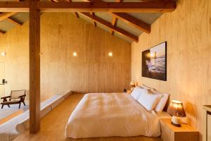 a bedroom with a large bed in a wooden room at DEAR MOM - Hotel & Cafe in Onjuku