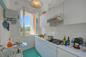 a white kitchen with a stove and a window at Studio Azur with Sea View Terrace - Happy Rentals in Cap d'Ail