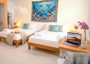 a room with two beds and a laptop on a desk at Centro Mornings, King & 2BR Suites, Sleeps 2-8, Kitchen WiFi AC, Beach, 5th Ave, ADO & Ferry 4 Min in Playa del Carmen