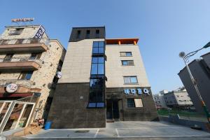 a tall brick building with windows on a street at Daecheon Sea Joa Pension in Boryeong