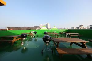 a group of tables and picnic tables with green walls at Daecheon Sea Joa Pension in Boryeong