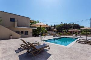 a pool with chairs and umbrellas next to a building at Casa Di Mare - Studios and Apartments with pool on the beach, by ZanteWize in Vasilikos