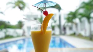 a glass of orange juice with a banana and an umbrella at El Cielo Resort in Dauin