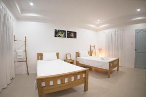 two beds in a room with white walls at El Cielo Resort in Dauin