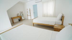 a white room with a bed and a chair at El Cielo Resort in Dauin +1 photo