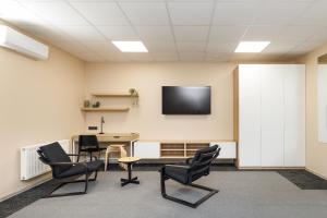 a room with a table and chairs and a tv on the wall at Air Kaunas apartment in Karmėlava