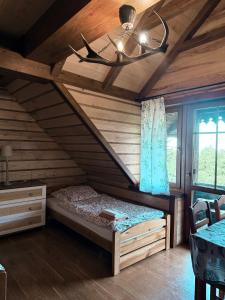 a bedroom with a bed in a wooden house at Hubertówka Dom in Ujanowice