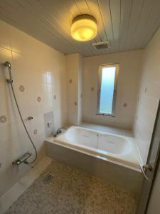 a bathroom with a large tub and a window at ホテル アクティ エクシブ in Asahi