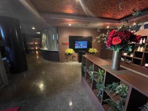 a lobby with a counter with flowers and a television at ホテル アクティ エクシブ in Asahi +4 photos