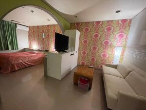 a bedroom with a bed and a tv and a couch at ホテル アクティ エクシブ in Asahi