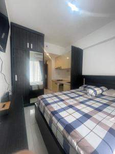 a bedroom with a bed with a blue and white blanket at APARTEMEN SKY HOUSE BSD in Samporo