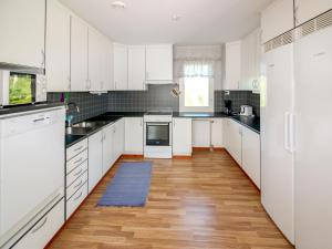 a kitchen with white cabinets and a wooden floor at Villa Björkholmen in Svartön
