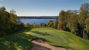 a golfer on a green with a lake in the background at Halsmo 6 in Kil