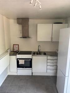 a kitchen with white cabinets and a sink and a stove at Halsmo 6 in Kil