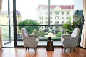 two chairs and a table in front of a large window at ARIA Hotel in Ninh Binh