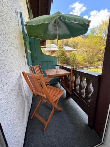 a table and a chair with an umbrella on a balcony at Haus Auerhahn Ferienwohnungen in Ramsau
