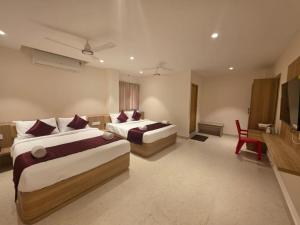 a hotel room with two beds and a television at Kovil Vaasam in Tiruchirappalli