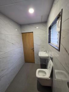 a bathroom with a toilet and a sink and a window at Kovil Vaasam in Tiruchirappalli +33 photos