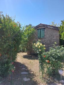 a garden with roses and a stone building at Maisonnette de caractère au calme in Fayence +7 photos
