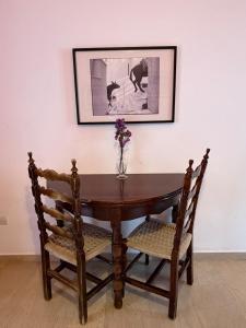 a wooden table with two chairs and a vase with flowers at Art & Motion Union - Guest Room 3 in Apoíkia +23 photos