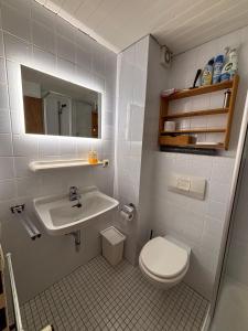 a white bathroom with a sink and a toilet at Haus Auerhahn Ferienwohnungen in Ramsau +28 photos