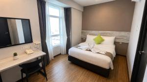 a hotel room with a bed and a desk and a television at The Leverage Lite (Kuantan) in Kuantan