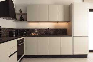 a kitchen with white cabinets and black appliances at Orien, Seaside Luxury Villa in Argassi