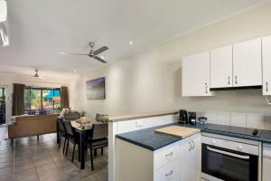 a kitchen with white cabinets and a dining room at Pearl Escape in Broome