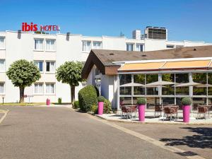 a hotel with tables and chairs in front of a building at ibis Chartres Ouest Luce in Chartres
