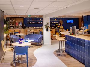 a restaurant with blue walls and tables and chairs at ibis Rennes Beaulieu in Cesson-Sévigné