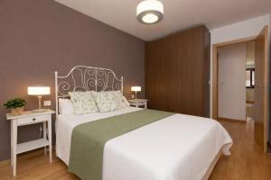 a bedroom with a large white bed with two tables and two lamps at Casa MiMar by BeValle in Panticosa