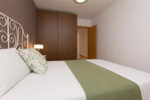 a bedroom with a white bed with a green and white blanket at Casa MiMar by BeValle in Panticosa