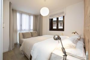 a white bedroom with two beds and a couch at Acentor Alpino by BeValle in Panticosa +23 photos